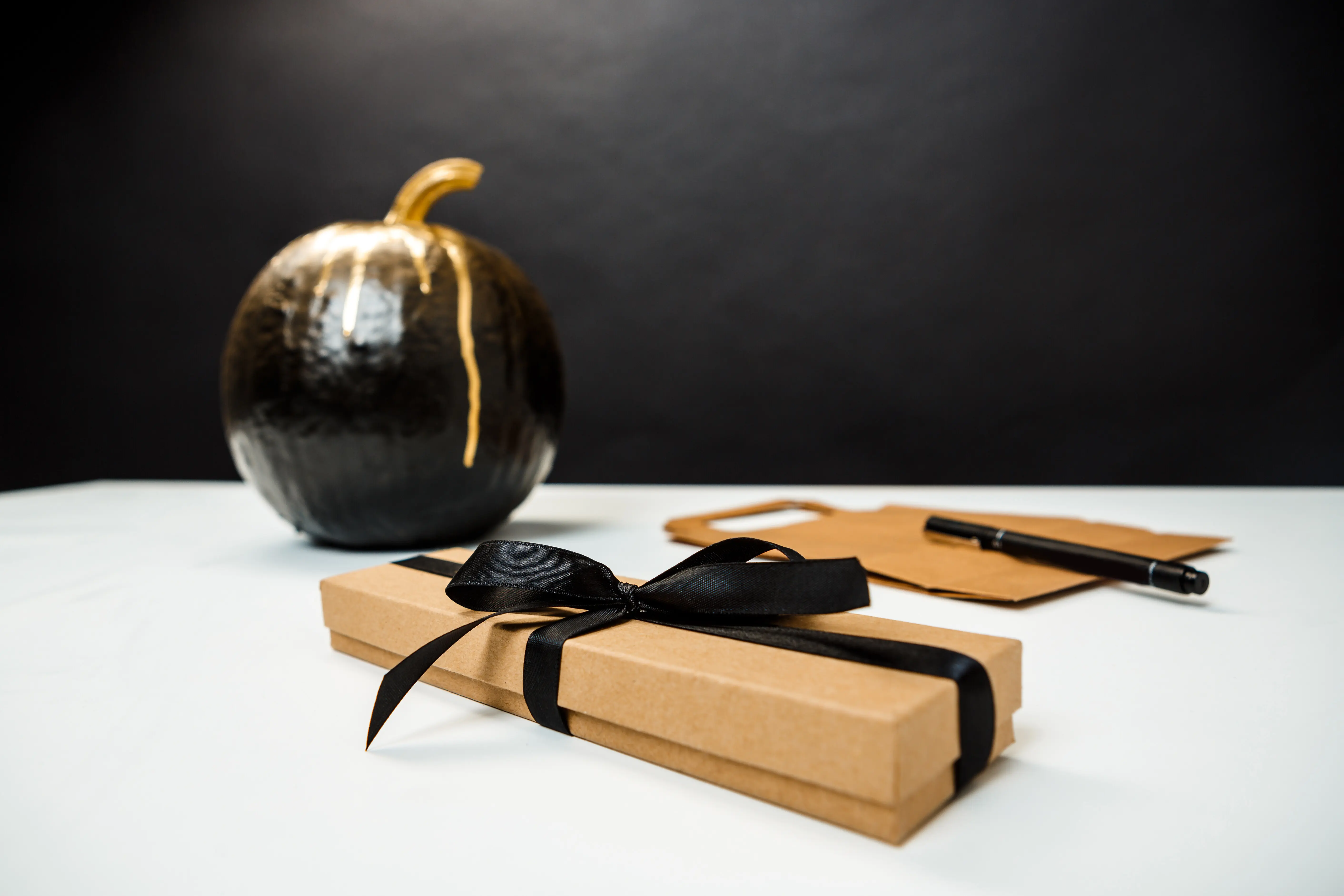 Halloween-Dekoration auf weißem Tisch vor schwarzer Wand